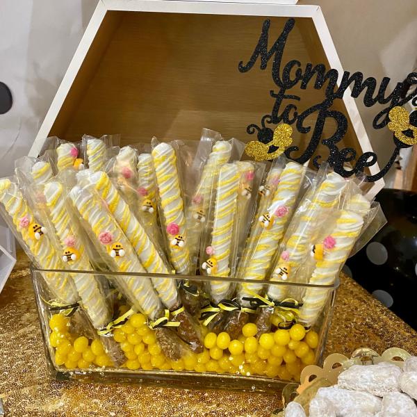 Chocolate covered pretzel rods in white and yellow with baby bees for a mommy to bee baby shower