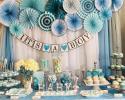 Sweet as can be little baby boy elephant, blue, white and silver themed baby shower dessert table with pinwheel fans and draped photo backdrop. Showcasing an array of desserts; candy jars, meringue kisses, cupcakes, cake pops, chocolate covered Oreo's and chocolate covered pretzel rods