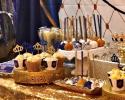 Royal blue and gold dessert table for little prince baby shower. Table contains cup cakes, cake pops and chocolate covered pretzel rods