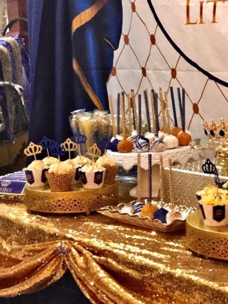 Royal blue and gold dessert table for little prince baby shower. Table contains cup cakes, cake pops and chocolate covered pretzel rods