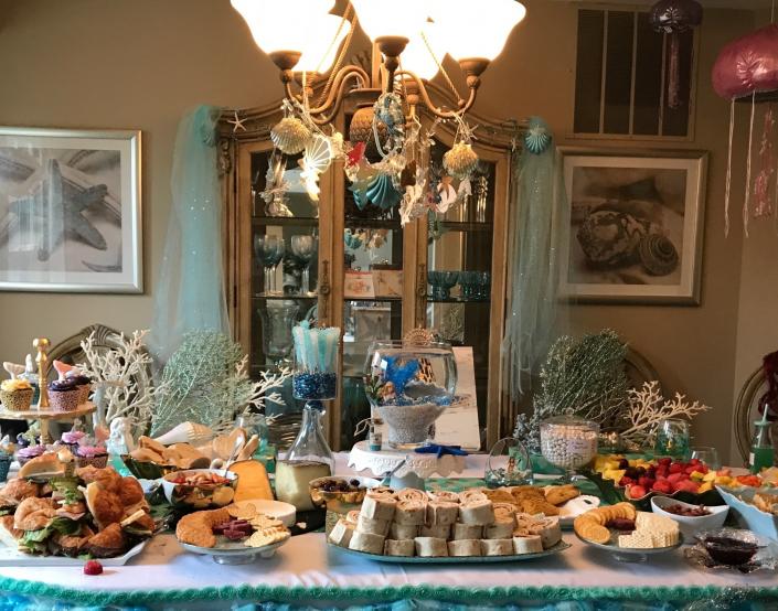 Mermaids, coral and sea shells decorate the buffet table. A few other decorations used for the under the sea themed birthday party were octopuses hung from the ceiling, star fish garlands, and a fish bowl as the centerpiece.   

